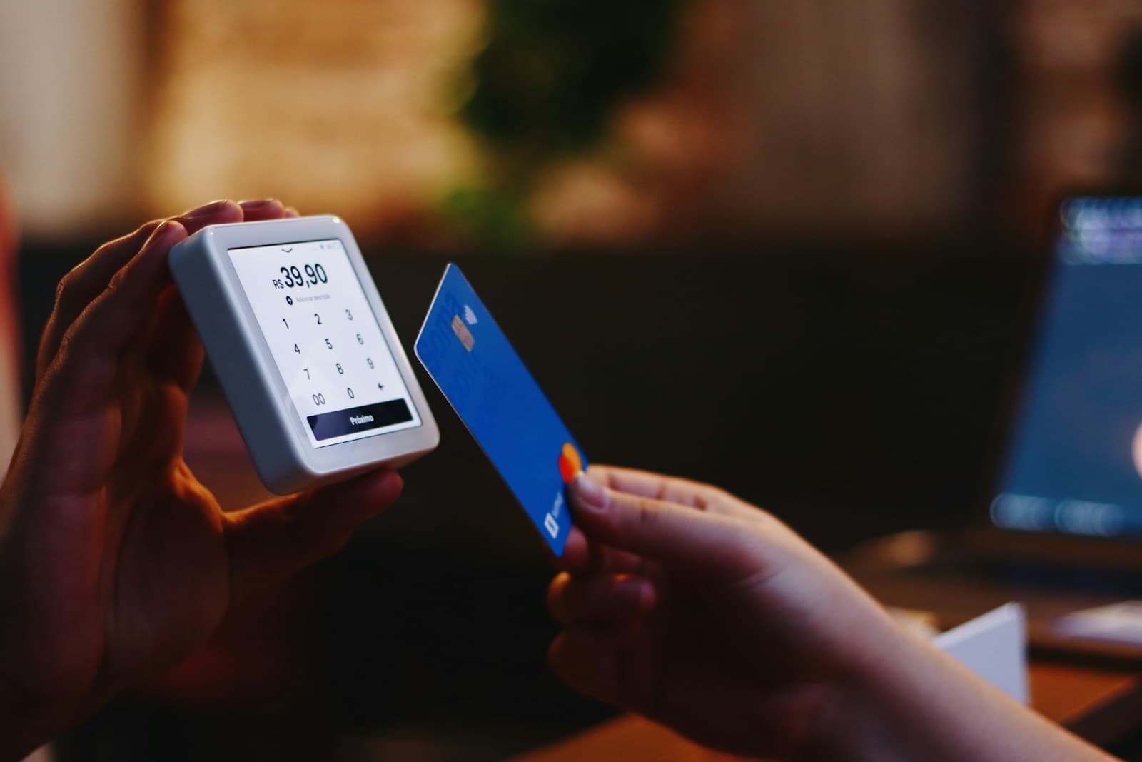 Une personne tient une carte de paiement d'une main et son téléphone de l'autre.