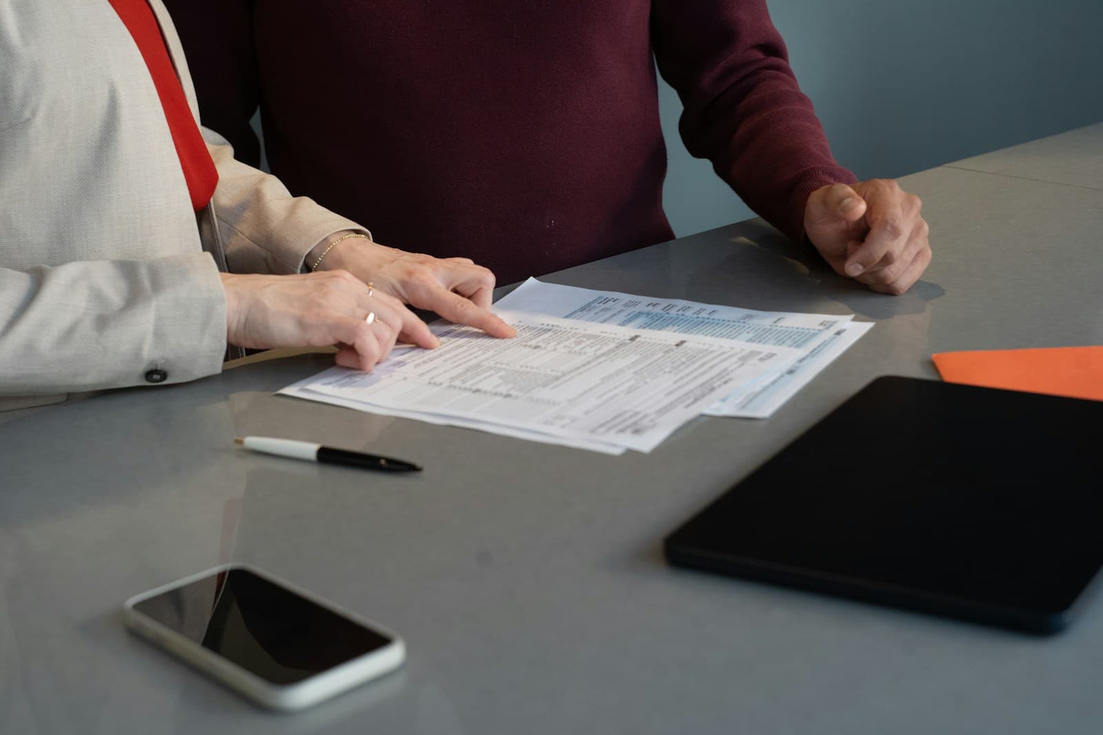 Deux personnes assises à une table examinent ensemble des documents papier.