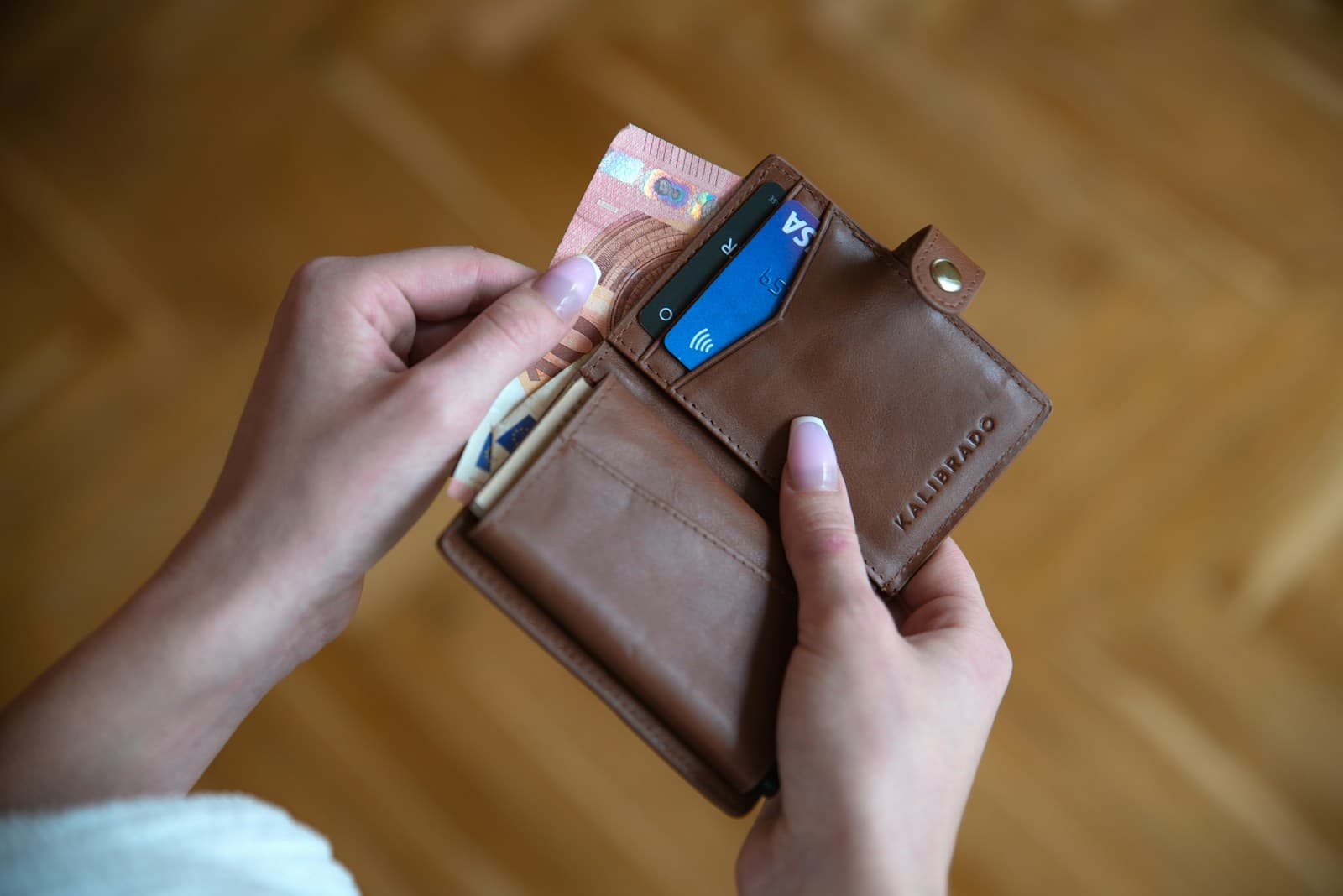 Une personne tient un portefeuille en cuir ouvert contenant plusieurs cartes.